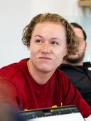 Portrait of Melissa, woman with reddish blonde hair wearing a red top, in an office setting